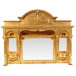 An ornate gold painted overmantel with an arched and ribbon tied cornice