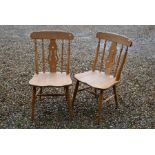 A pair of modern beech saddle seated side chairs with turned legs and stretchers