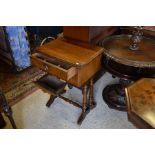 An Edwardian walnut sewing table on twin turned supports