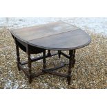 An oak drop leaf dining table on turned gateleg action supports