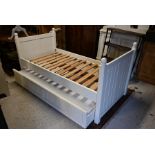 A cream painted wood panelled single bed and trundle