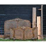 A Louis XV style carved walnut and cane panelled double bed frame