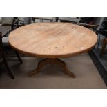 A stained pine circular dining table