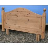 An arched and panelled stained pine double headboard