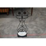 A wrought and cast black metal umbrella stand