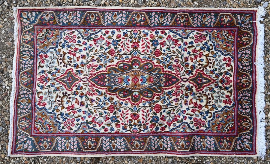 A Persian cream ground Kirman rug, 140 cm x 85 cm