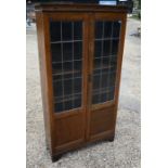 An oak bookcase with leaded part-glazed and panelled doors