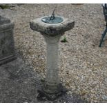 A weathered cast stone column sun dial