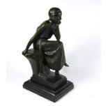 A brown bronze sculpture of a seated 1920's woman