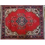 An old Persian Heriz rug with red ground and floral medallions
