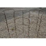 A trio of weathered steel curved garden plant frames