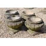 A set of four weathered cast-stone garden planters