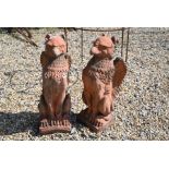 A pair of composite stone cast griffins in aged terracotta finish