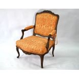 An antique carved walnut framed French fauteuil