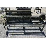 An old pair of large weathered wrought iron framed wood-slat garden benches