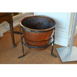 An antique copper tub within an iron tripod cradle