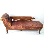 A late 19th century battered buttoned burgundy leather walnut framed chaise