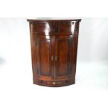 A George III mahogany hanging barrel front corner cupboard with drawer