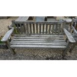 A weathered and slatted teak garden three seater bench