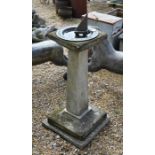 A weathered stone pedestal sun dial