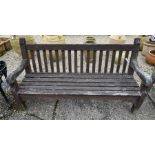 A stained and weathered teak three-seater garden bench