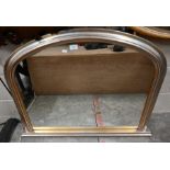 An arched overmantle mirror with silvered frame