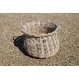 A large circular wicker twin handled log basket