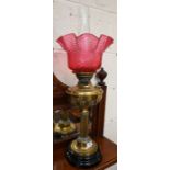 Victorian brass oil lamp with fluted pillar and cranberry shade