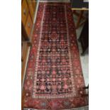A Persian Hamadan dark ground runner with a stylised floral design, red border, 290 x 105 cm
