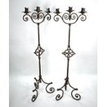 A pair of heavy wrought iron three candle tripod stands in the 17th century style