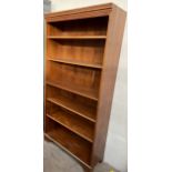 A reproduction yew bookcase with a moulded dentil cornice and shelves on bracket feet