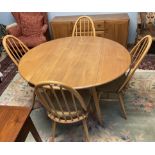 An Ercol drop leaf dining table together with four stick back dining chairs and a sideboard