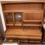 A teak wall unit, with shelves and glazed cupboards,