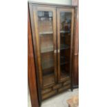 A 20th century mahogany effect display cabinet with glass doors and glass shelves above an