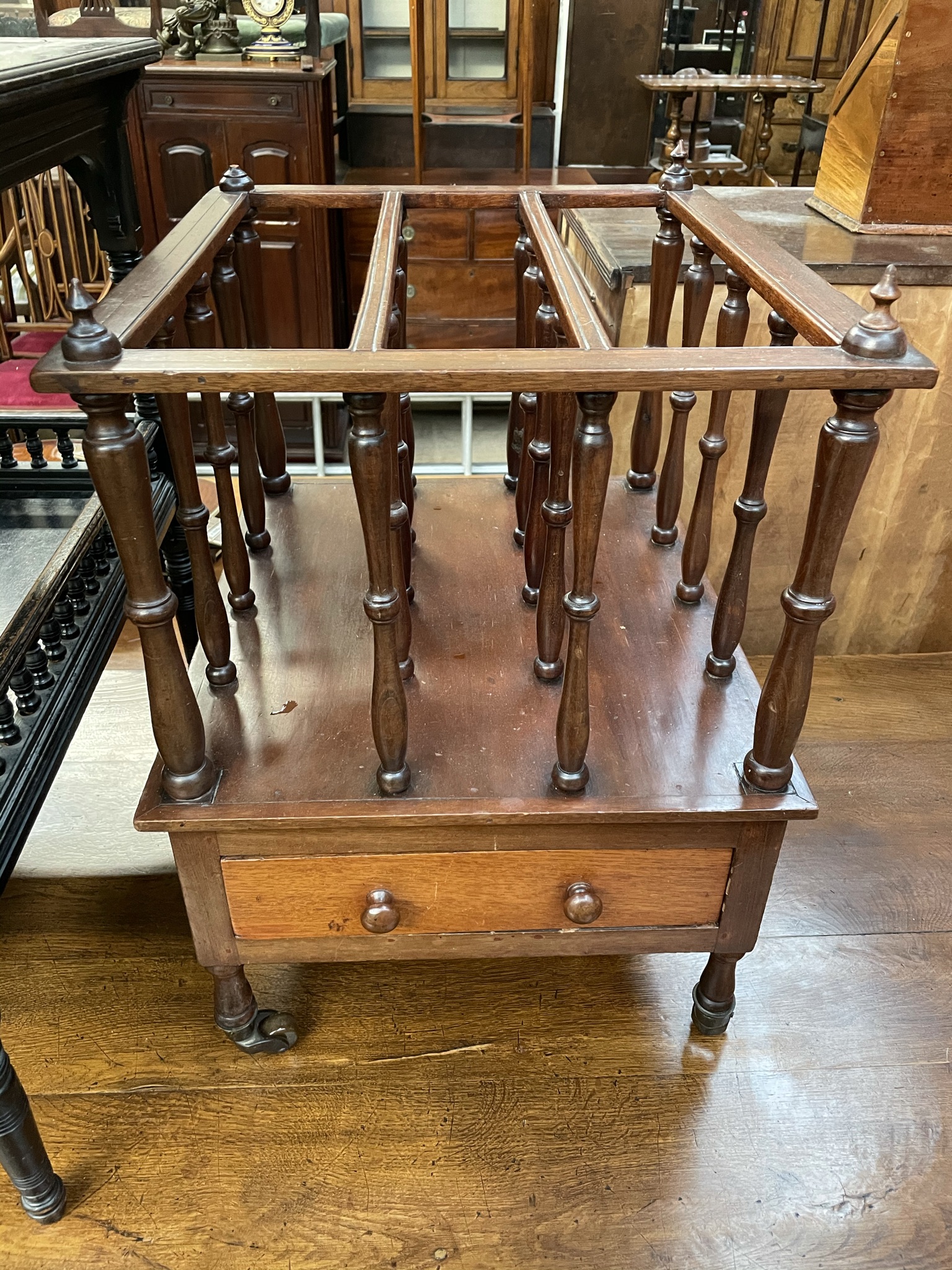 A Victorian mahogany Canterbury with three divisions above a base drawer on turned legs and casters