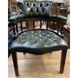A green leather button back upholstered captain's chair