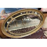A 19th century gilt gesso wall mirror of oval form with a gadrooned rim and reeded inner oval
