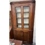 A 19th century mahogany standing corner cupboard with a pair of glazed doors to the top and