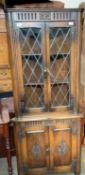 A 20th century oak standing corner cupboard with leaded glazed doors to the top and panelled doors