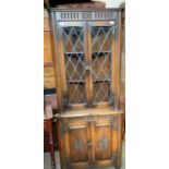 A 20th century oak standing corner cupboard with leaded glazed doors to the top and panelled doors