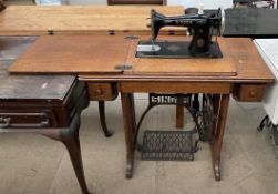 An oak Singer sewing machine table with a fold over top and treadle base
