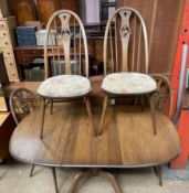 An Ercol extending dining table and four swan back chairs