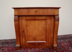 A Biedermeier style side cabinet with a rectangular crossbanded top above a frieze drawer and a