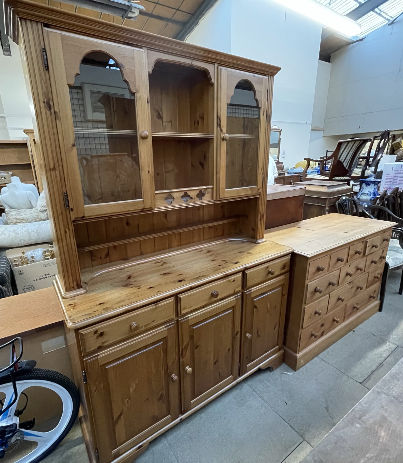 A modern pine dresser with a glazed top and cupboard base together with a pine chest of drawers