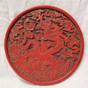 A decorative plaque decorated with a dragon amongst clouds in the style of cinnabar lacquer,