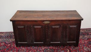 An 18th century oak coffer, the planked rectangular top above an inlaid four panel front on stiles,