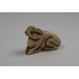 A late 19th century bone netsuke of a recumbent deer, signed to the base,