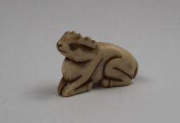 A late 19th century bone netsuke of a recumbent deer, signed to the base,