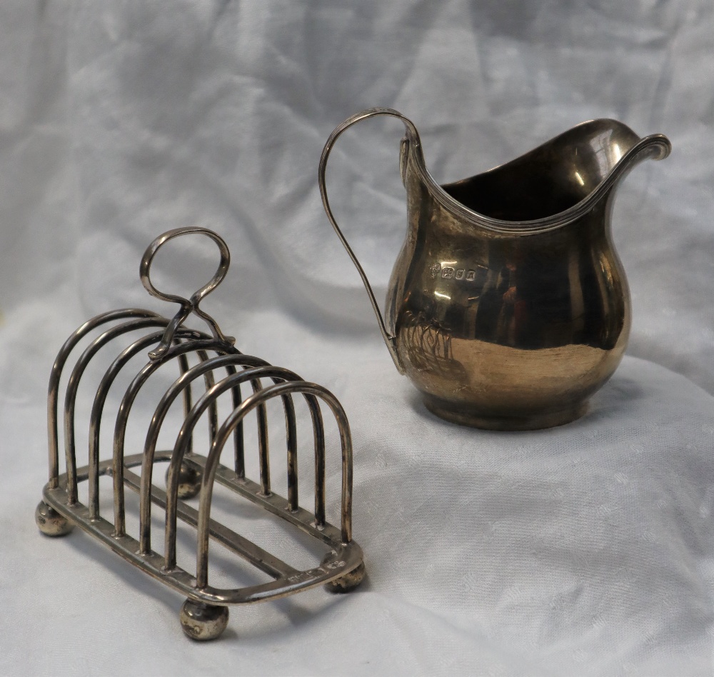 A George V silver cream jug of baluster form with a line decorated rim and handle, London, 1936,