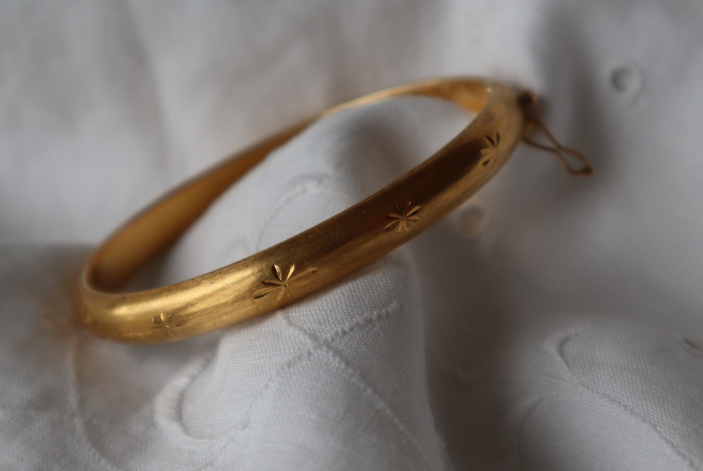 An 18ct gold hinged bracelet with star decoration,